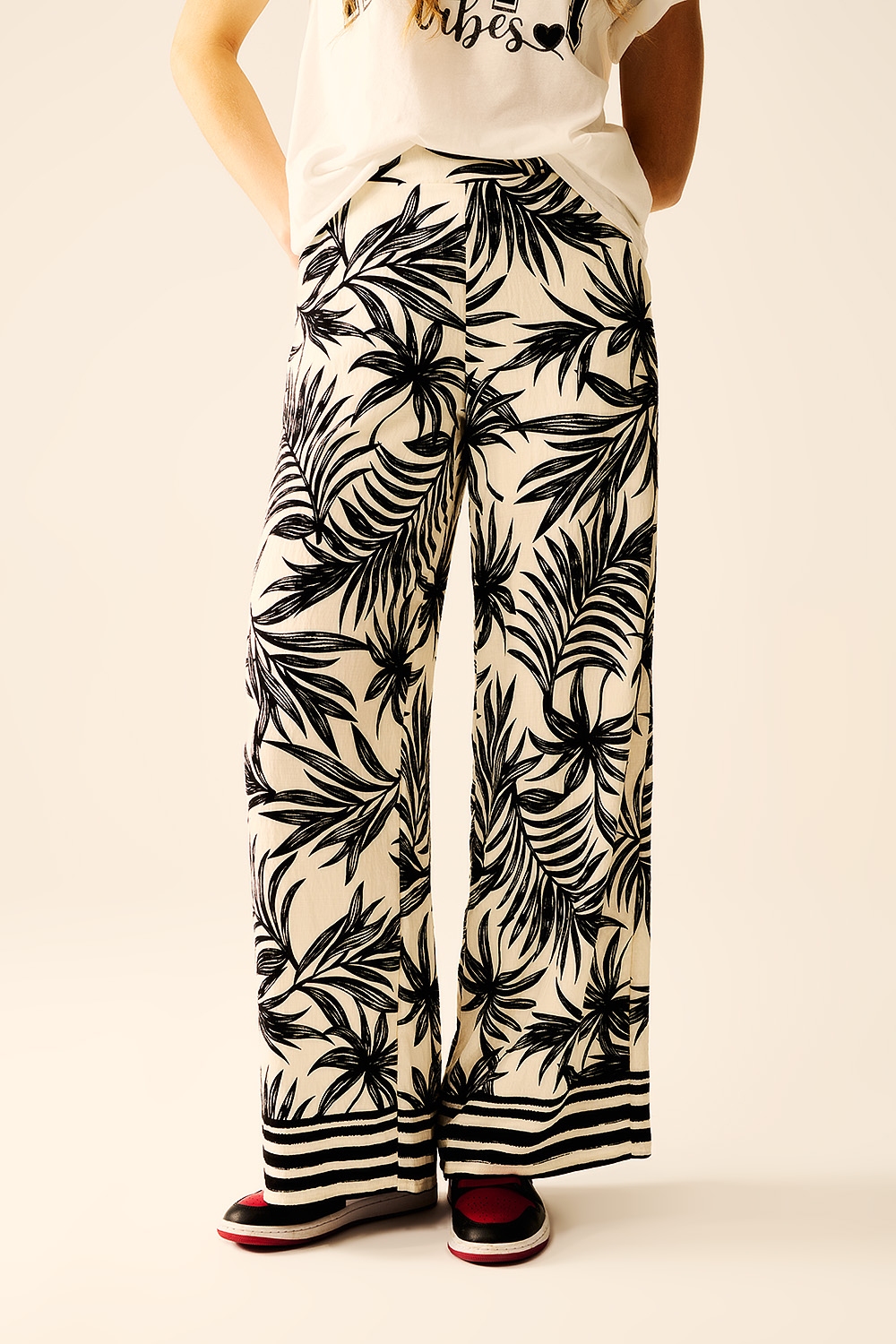 Pantalones de pierna ancha en blanco con detalle floral en negro Pantalones de pierna ancha en blanco con detalle floral en negro