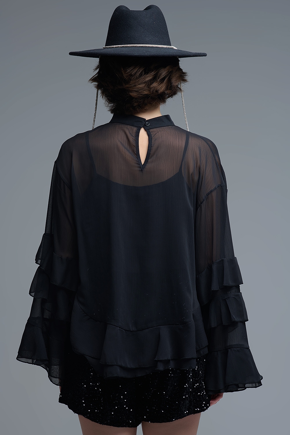 Blusa negra de gasa con volantes y transparencias estilo capa