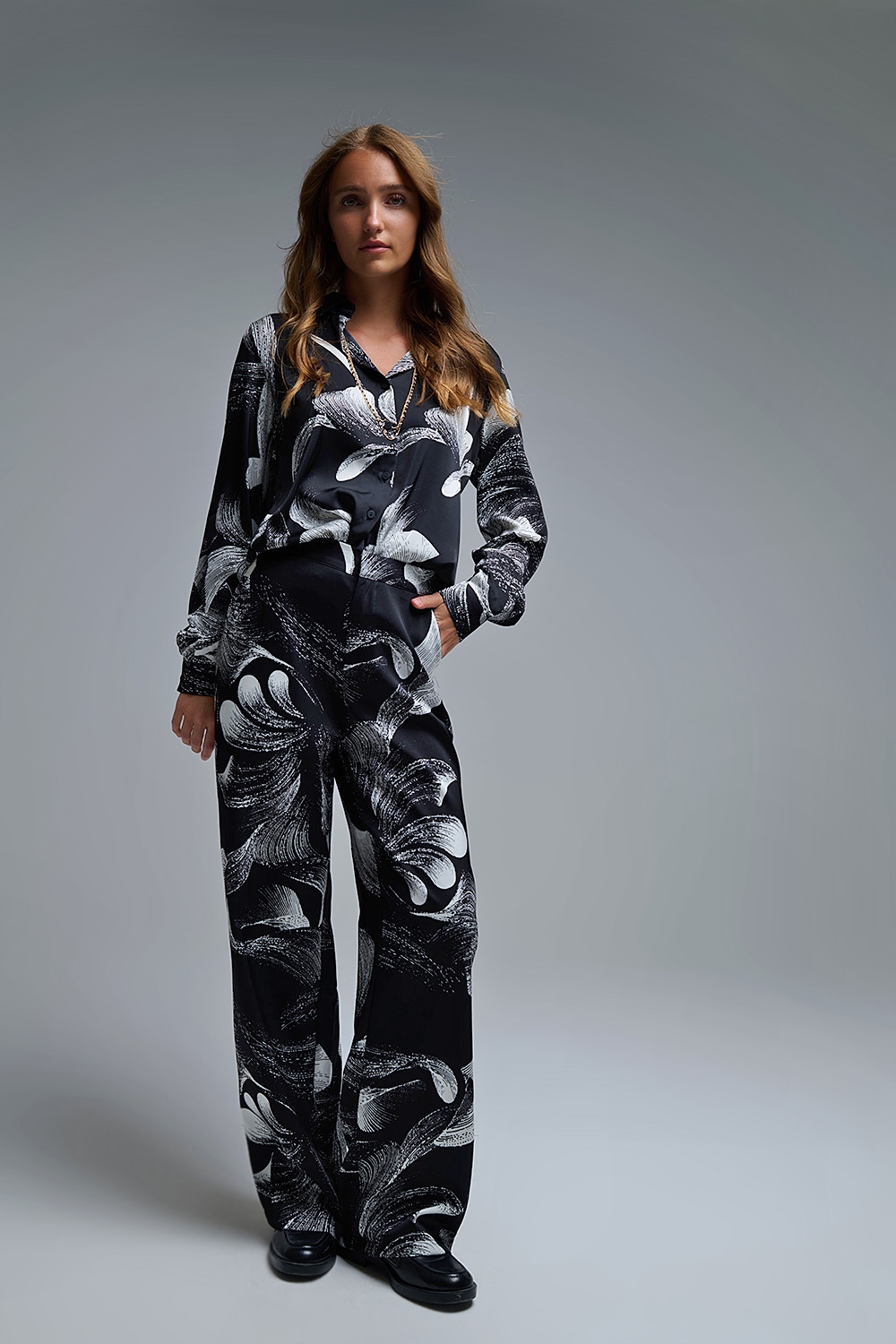 Elegante pantalón negro estampado de pata ancha en tejido satinado Elegante pantalón negro estampado de pata ancha en tejido satinado