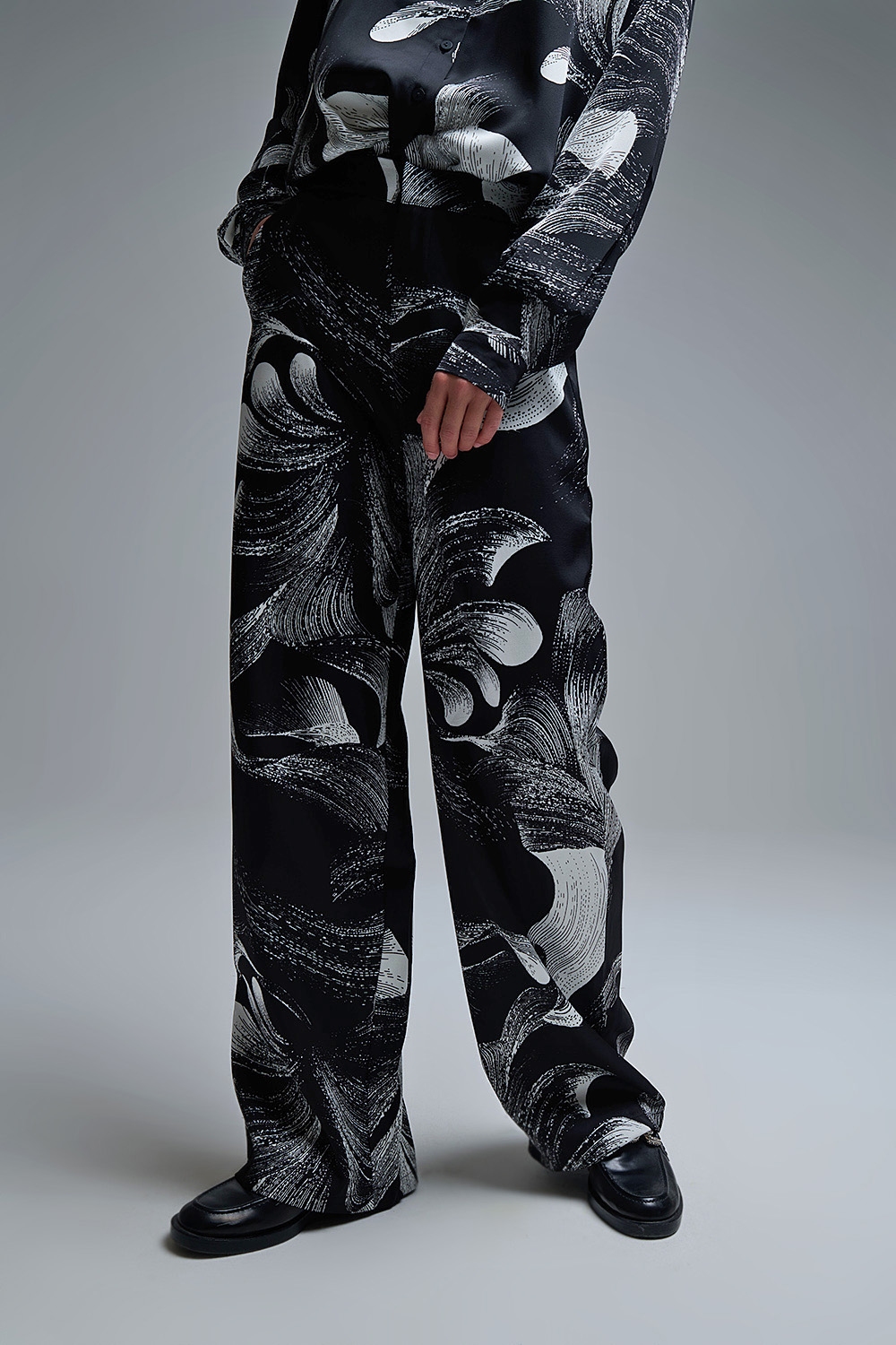 Elegante pantalón negro estampado de pata ancha en tejido satinado Elegante pantalón negro estampado de pata ancha en tejido satinado