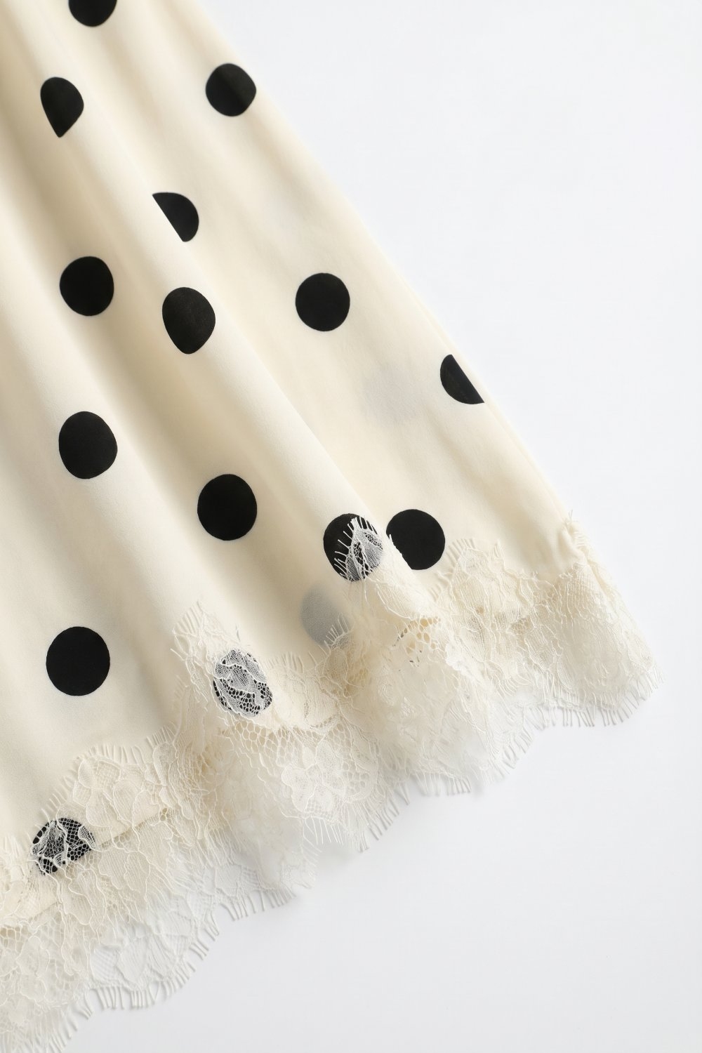 Falda midi asim&eacute;trica de sat&eacute;n con estampado de lunares en color crema y ribete de encaje